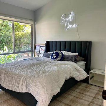 Néon blanc « Great Dane » installé au-dessus d’un lit dans une chambre, sur un support transparent