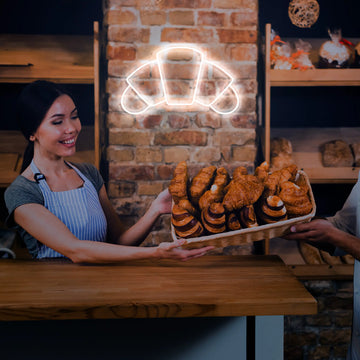 Close-up of the Croissant Neon Sign, glowing with golden and warm hues, adding a French culinary charm to any room.